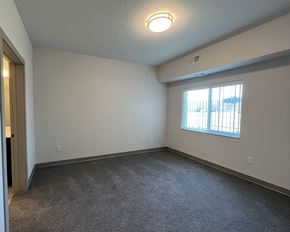 Lake City apartment for rent - an empty living room with a window and carpet