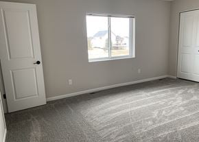Belle Plaine townhouse for rent - A room with a carpeted floor and a window showing a view of houses outside.