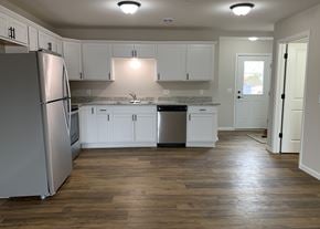 Belle Plaine townhouse for rent - A kitchen with white cabinets and a wooden floor.