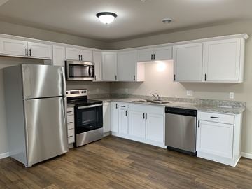 Belle Plaine townhouse for rent - A kitchen with white cabinets and a granite countertop.