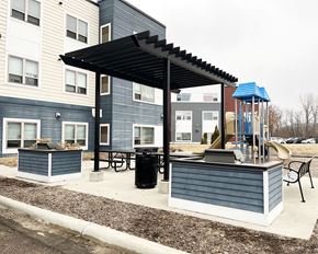 Mankato apartment for rent - A playground area with a slide and a canopy is located in front of a building.
