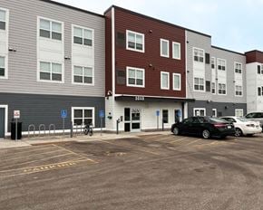 Mankato apartment for rent - A parking lot in front of a multi-story apartment building with a black car parked in the lot.