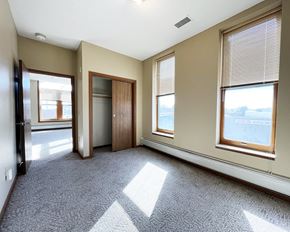Olivia apartment for rent - an empty living room with three windows and a door