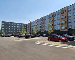 St. Louis Park apartment for rent - a parking lot with cars in front of a large building