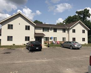 Willmar apartment for rent - a large white building with two cars parked in front of it