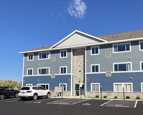 Owatonna apartment for rent - A blue building with a parking lot in front.