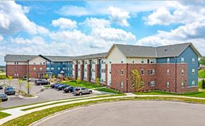 Shakopee apartment for rent - A large building with a parking lot in front.