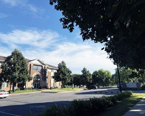 St. Peter apartment for rent - A parking lot in front of a building with trees and a clear sky.