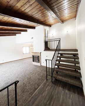 Mankato townhouse for rent - A wooden staircase with a metal railing leads up to a second floor.