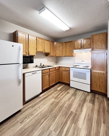 New Ulm apartment for rent - A kitchen with wooden cabinets and white appliances.