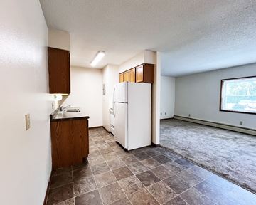 Northfield apartment for rent - A kitchen with a white refrigerator and brown cabinets.