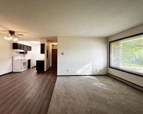 Mankato apartment for rent - A spacious room with a ceiling fan and a kitchen area in the background.