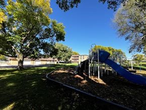 Mankato apartment for rent - A playground with a blue slide and a tree with yellow leaves.