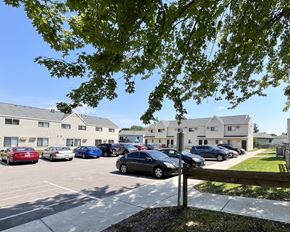 Rochester apartment for rent - A parking lot with cars and apartment buildings in the background.