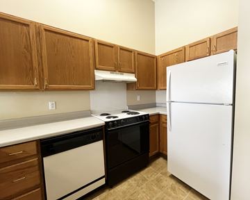 Cannon Falls apartment for rent - A kitchen with brown cabinets and a white refrigerator.