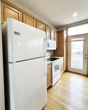 Faribault townhouse for rent - A white refrigerator in a kitchen with wooden cabinets.