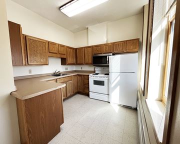 Olivia apartment for rent - an empty kitchen with white appliances and wooden cabinets