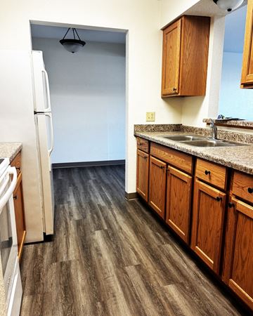 Willmar And  Alexandria apartment for rent - A kitchen with a white refrigerator and wooden cabinets.