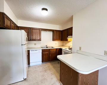 North Mankato apartment for rent - an empty kitchen with white appliances and wooden cabinets