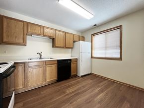 Mankato townhouse for rent - an empty kitchen with wooden cabinets and a refrigerator