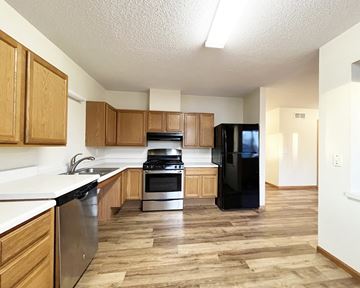 Mankato townhouse for rent - A kitchen with wooden cabinets and a black refrigerator.