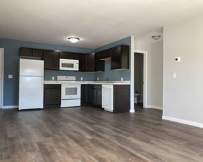 Owatonna apartment for rent - A kitchen with a white refrigerator, black cabinets, and a white oven.
