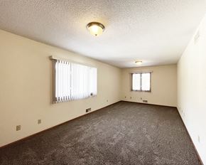 Mankato townhouse for rent - A spacious room with carpeted floor and two windows.