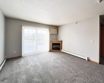 Worthington apartment for rent - A sparsely furnished living room with a fireplace and sliding glass doors.