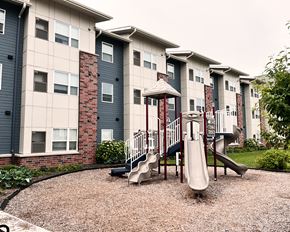 Shakopee apartment for rent - A playground with a slide in front of apartment buildings.