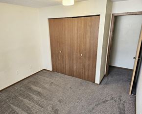 Cannon Falls apartment for rent - A room with a brown door and carpeted floor.
