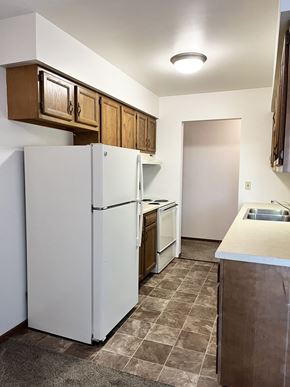 North Mankato apartment for rent - A kitchen with a white refrigerator and brown cabinets.