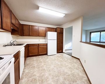 Lonsdale apartment for rent - A kitchen with brown cabinets and a white refrigerator.