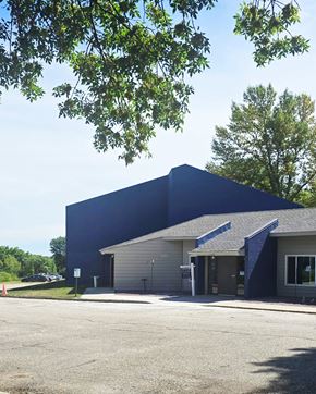 Windom apartment for rent - A blue building with a parking lot in front.