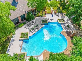 An aerial view of a resort style pool with chairs and trees