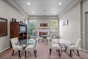 A living room with a glass table and white chairs.