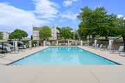 Olathe apartment for rent - a swimming pool with chaise lounge chairs and trees in the background at Millcreek Woods Apartments, Kansas, 66061