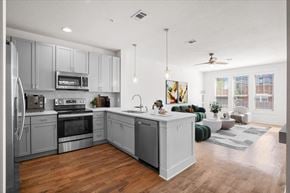 Kansas City apartment for rent - A large, open gourmet kitchen with stainless steel appliances including microwave and dishwasher, hardwood floors, and pendant lighting at Mirabelle Luxury Apartments, Kansas City