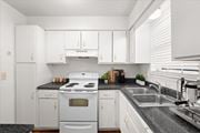 Overland Park townhouse for rent - a kitchen with white appliances and white cabinets at Sheridan Ridge Townhomes Apartments, Kansas, 66212