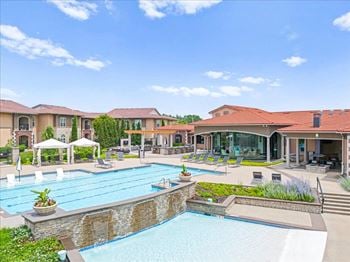 A large swimming pool with lounge chairs in front of a building