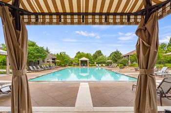 A pool area with a striped canopy over it.