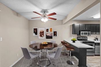 A dining room with a kitchen and a ceiling fan