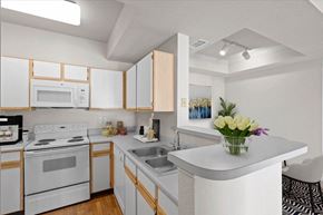Lenexa apartment for rent - An open kitchen with white appliances, grey countertops, and white storage cabinets. at Crescent Apartment Homes, Lenexa, KS, 66219