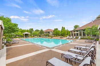 A large swimming pool surrounded by lounge chairs and trees.