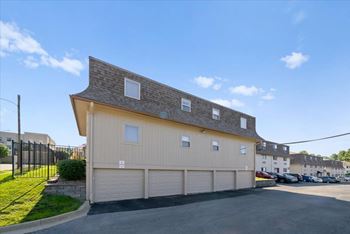 A two-story building with a garage door and a driveway in front.