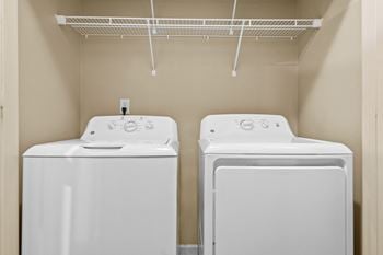 Two white front loading washing machines in a small laundry room.