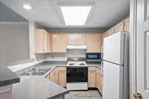 Overland Park apartment for rent - A kitchen with a white refrigerator, sink, and stove.at The Claremont Apartment Homes, Overland Park, 66210