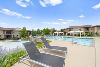 A swimming pool with two lounge chairs in front of a building