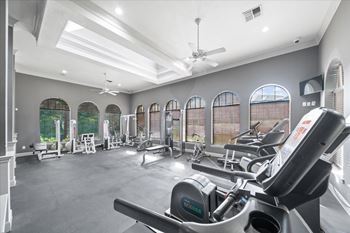 A spacious gym with a variety of equipment and large windows.