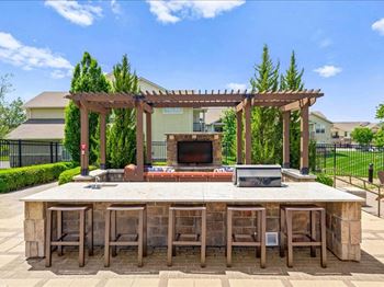 A large outdoor kitchen with a bar and a fireplace