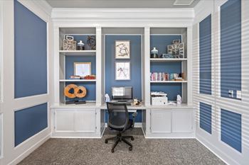 A room with a desk and a chair in front of a wall with shelves.